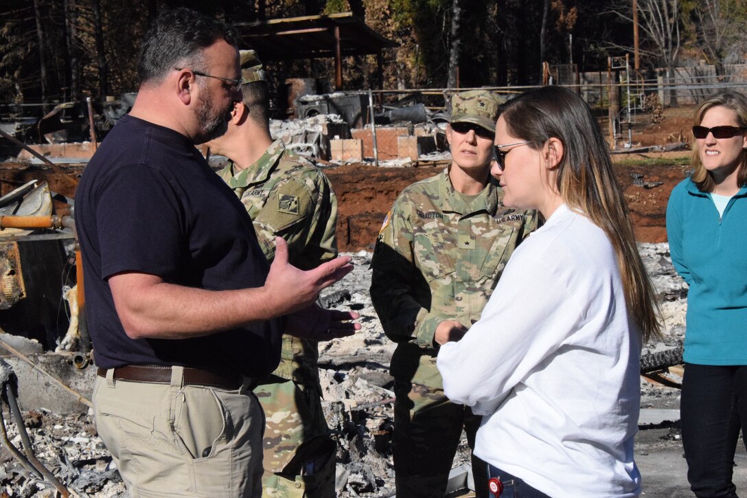 woman speaks to man at burnt-down building