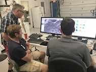 Dr. James Campbell (standing), Dr. Anthony Bucholtz (center) and Dr. David Peterson monitor real-time satellite imagery of cirrus clouds over the northern Gulf of Mexico. (