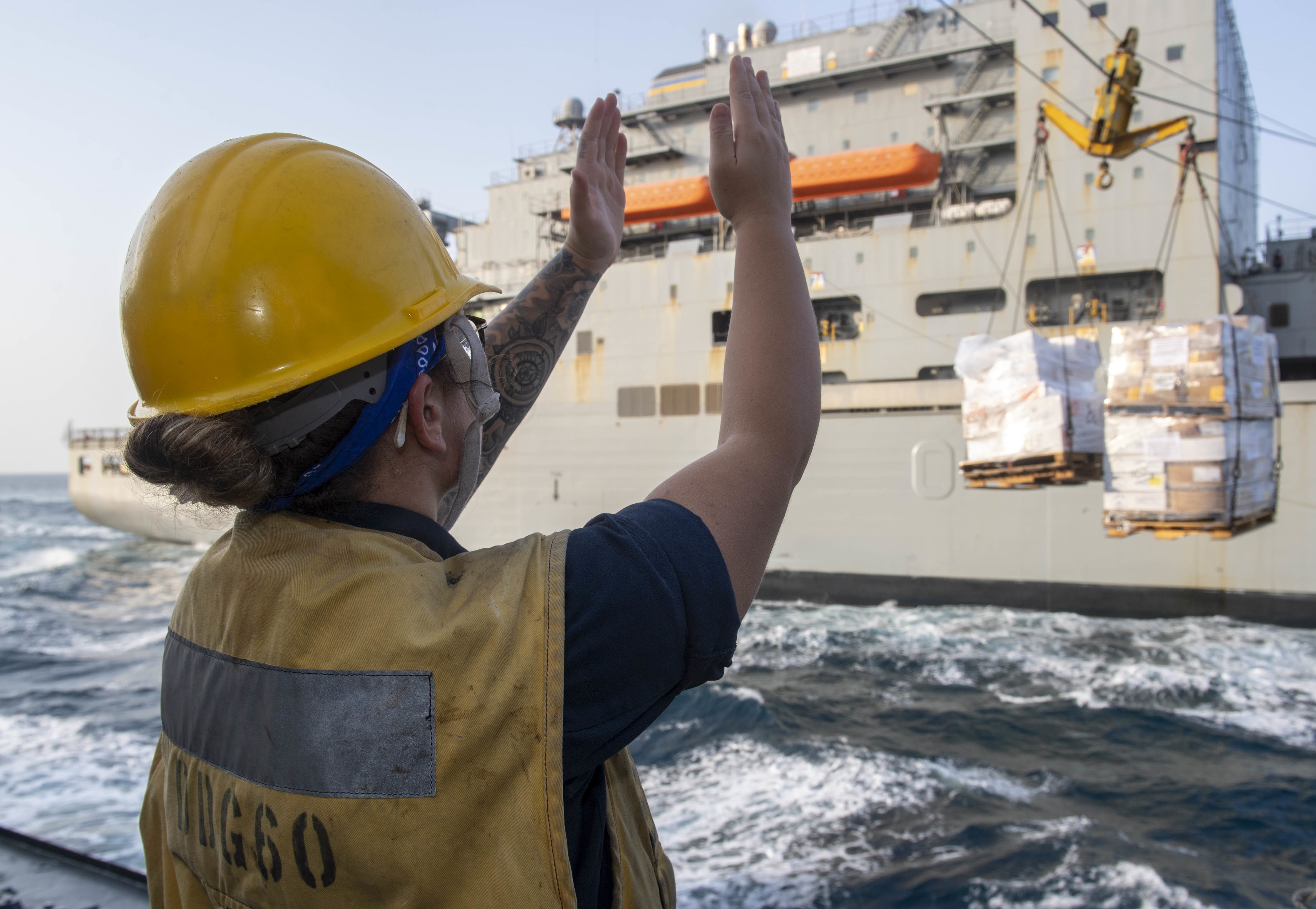 Boatswain’s Mate 2nd Class Jamie Skinner, assigned to the guided-missile destroyer USS Paul Hamilton (DDG 60), signals the Military Sealift Command dry cargo and ammunition ship USNS Matthew Perry (T-AKE-9) the distance of incoming cargo during a replenishment-at-sea Aug. 27, 2020.