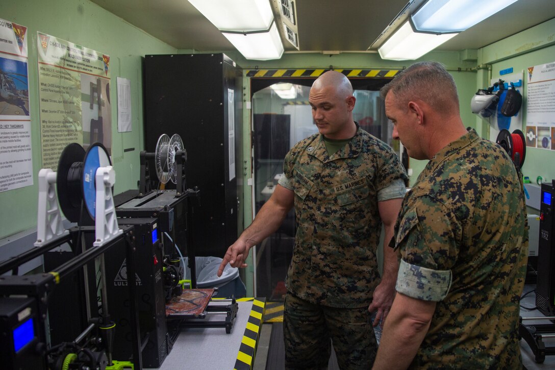 U.S. Marine Corps SSgt Michael P. Burnham, a machinist with Marine Aviation Logistics Squadron 36, briefs Maj Matthew M. Mulherin, an electronics maintenance officer with Marine Air Support Squadron 2, on the process of 3D printing on MCAS Futenma, Okinawa, Japan, April 6, 2020. The Marines of MALS-36 are working to produce mask frames and face shields for use in the fight against COVID-19. (U.S. Marine Corps photo by Lance Cpl. Ethan M. LeBlanc)