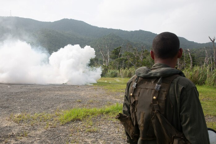U.S. Marine Corps Lance Cpl. Zachary D. Torres, a helicopter crew chief with Marine Heavy Helicopter Squadron 361, deploys an M18 smoke grenade to signal the 33rd Rescue Squadron, 18th Wing, to pick up the U.S. Marines and Sailors with 1st Marine Aircraft Wing during a Combat Search and Rescue training event at Okinawa, Japan, Aug. 6th 2020. The exercise was held as part of Weapons and Tactics Instructor Primer to enhance the interoperability, relationships and communication between U.S. Marine Corps air, ground components with the U.S. Air Force. (U.S. Marine Corps photo by Cpl. Ethan M. LeBlanc)