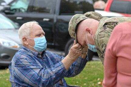 Retired Sgt. 1st Class Eugene Patton Sr. affixes the insignia on his son 1st Sgt. Eugene Patton Jr. patrol cap during a promotion ceremony on October 20, 2020.