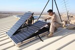 U.S. Marine Corps Cpl. Robert G. Sutton, left, and Cpl. Moses E. Perez, field wireman with Combat Logistics Regiment 15 install new solar panels on Combat Outpost Shukvani, Helmand province, Afghanistan, Nov. 19, 2012. Sutton and Perez installed the solar panels to provide power to radios, laptops, and computers in the event of power outages.