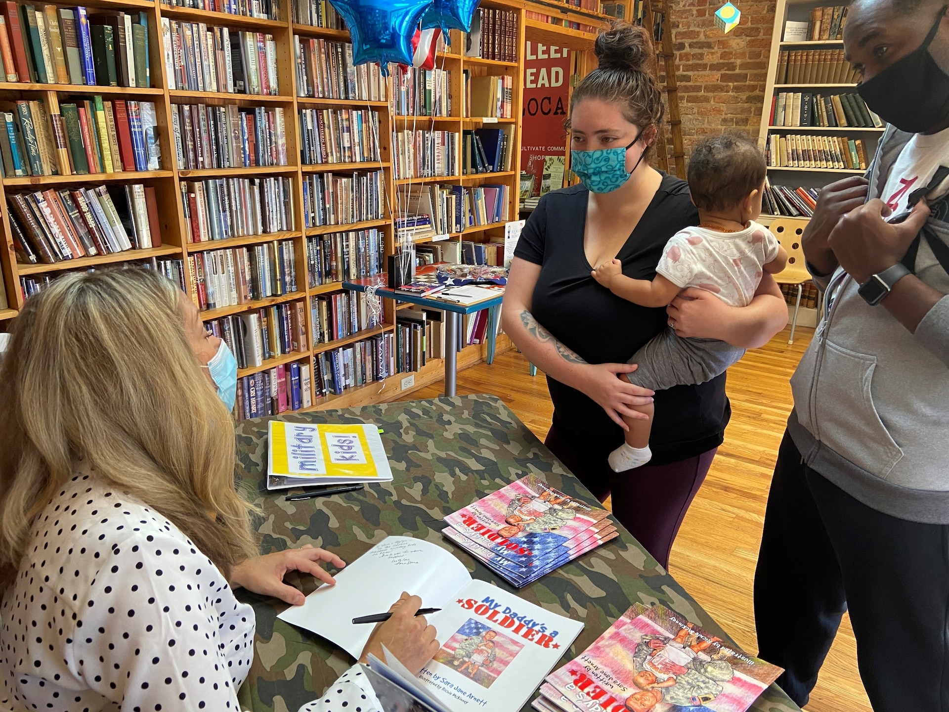 Sara Jane Arnett, wife of U.S. Army Maj. Samuel Arnett of U.S. Army Central, discusses military family life and resources with Kendra Williams (left) and U.S. Air Force Tech. Sgt. Dell Williams (right) for their daughter, Skylyn (center) during an author event promoting her children’s book, My Daddy’s a Soldier, in Camden, SC, Nov. 21, 2020.  The Arnetts, who are Kentucky natives, have worked for nearly two decades to support military families and communities. Sara wrote a book to help children of service members cope with challenges associated with deployments, separations and constant relocations.  (U.S. Army photo by Capt. Paul O’Daniel)