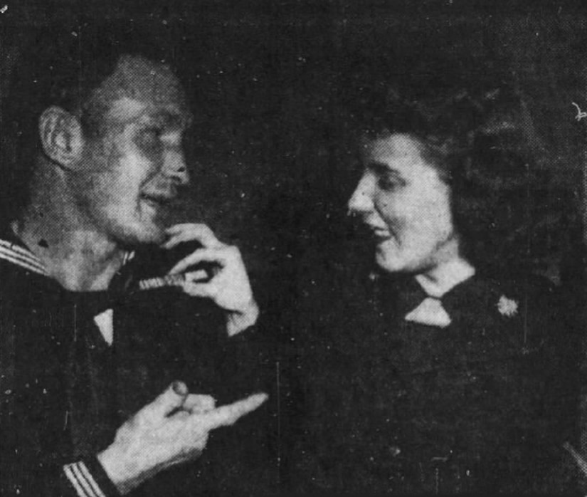 Man and woman in Coast Guard uniforms speak to one another.