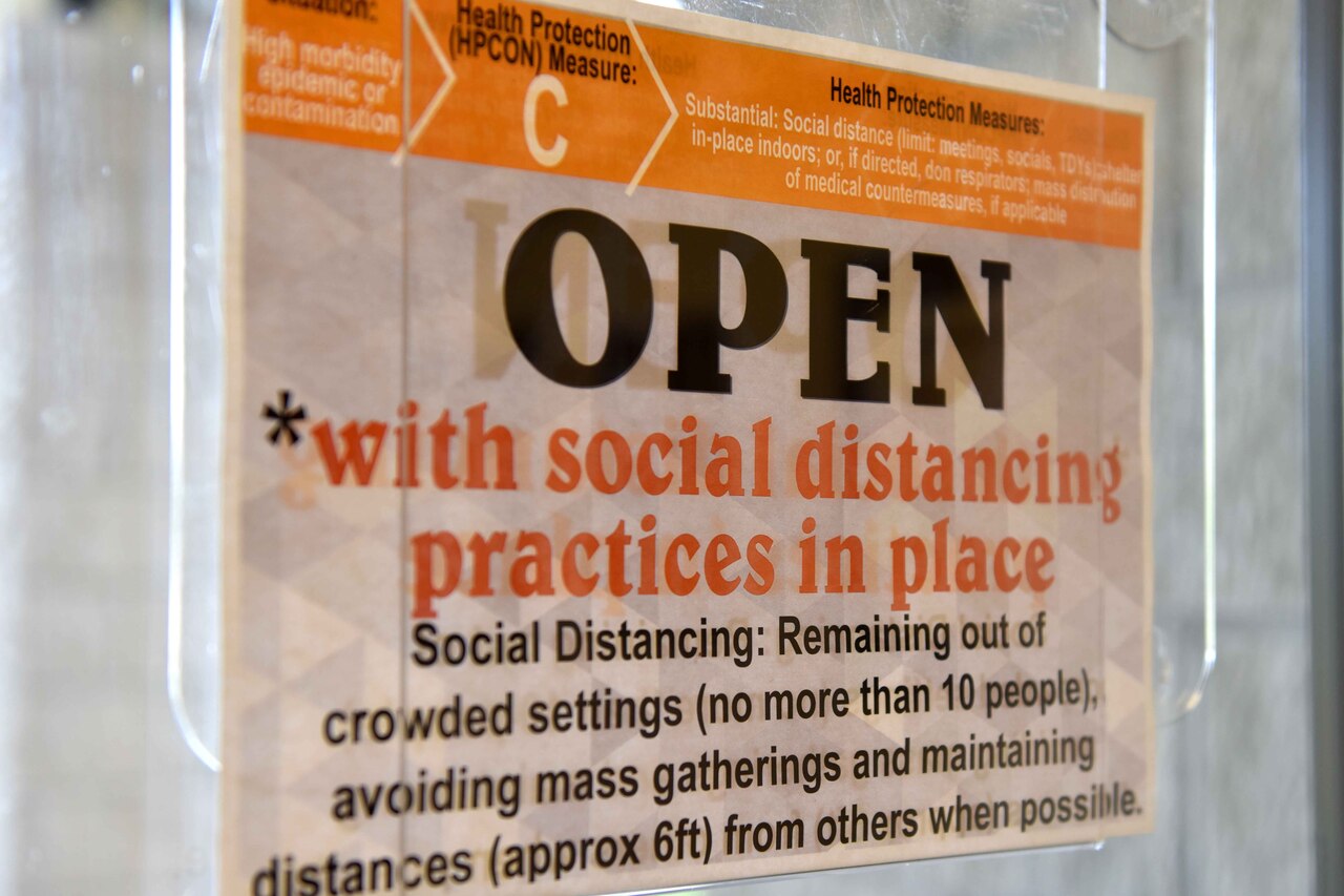 A COVID-19 precaution sign hangs on a door.
