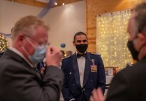 A group of three men talk in a circle with masks on.