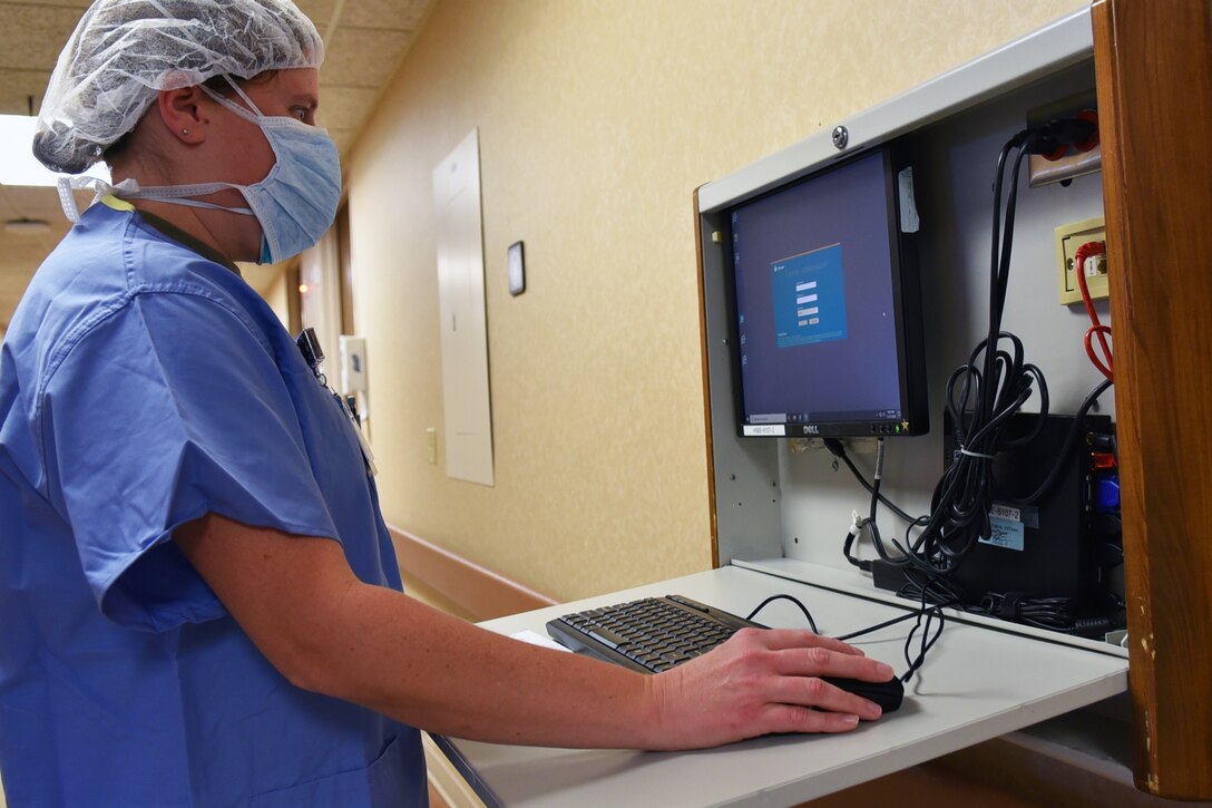 A woman wearing a face mask inputs medical information into a computer