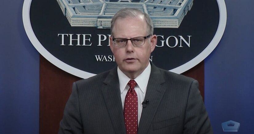 A man is speaking and behind him is a sign stating that he is at the Pentagon.