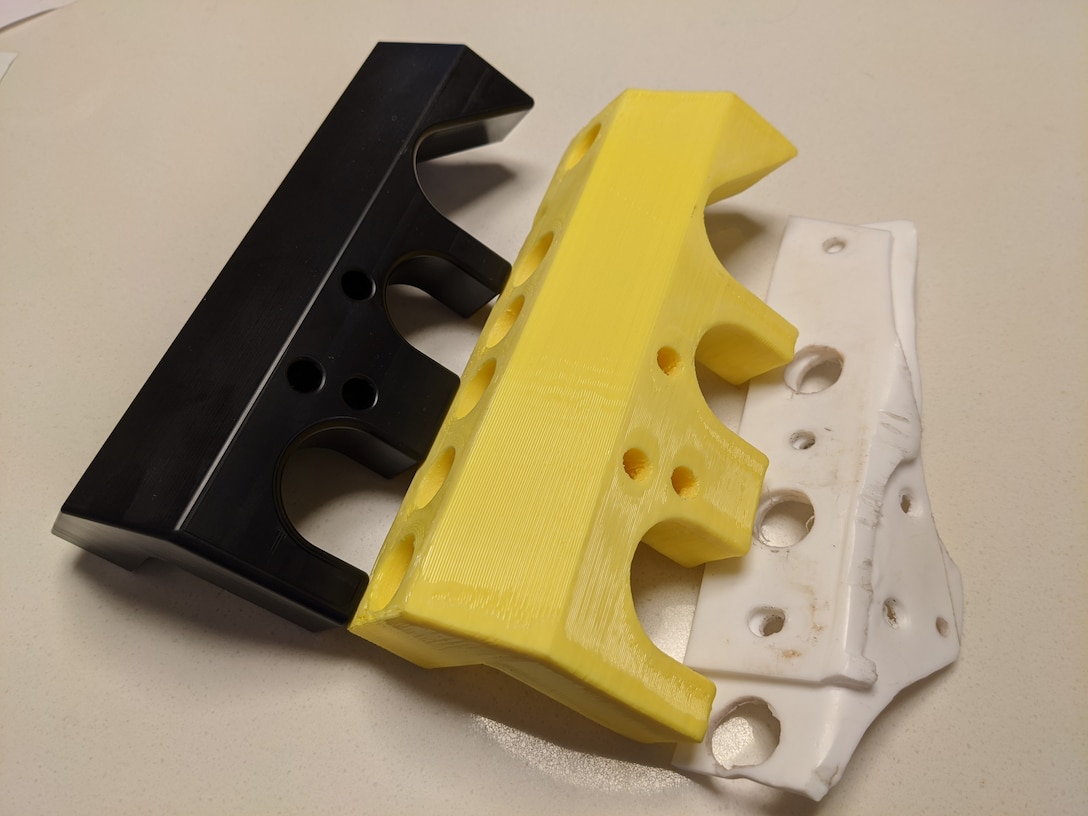 Three pieces of reverse engineered prototypes were 3D printed by the Naval Surface Warfare Center Panama City Division (NSWC PCD) Additive Manufacturing Laboratory. These prototypes were a proof of concept for the NSWC PCD Fabrication and Prototype Shops to rapidly deliver a solution to meet emerging fleet needs. Pictured from left to right: Computer numerical control Delrin plastic prototype, 3D printed polyethylene terephthalate, hand-cut plastic proof of concept.