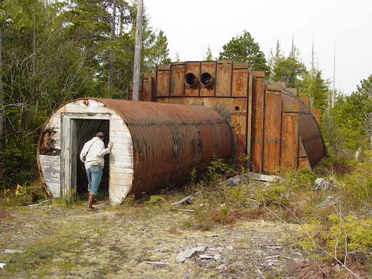 An individual peers into an abandoned military structure on Annette Island. Starting in 1940, the military and other federal agencies used the island for various purposes, leaving structures and debris behind as the land changed hands.