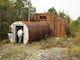 An individual peers into an abandoned military structure on Annette Island. Starting in 1940, the military and other federal agencies used the island for various purposes, leaving structures and debris behind as the land changed hands.