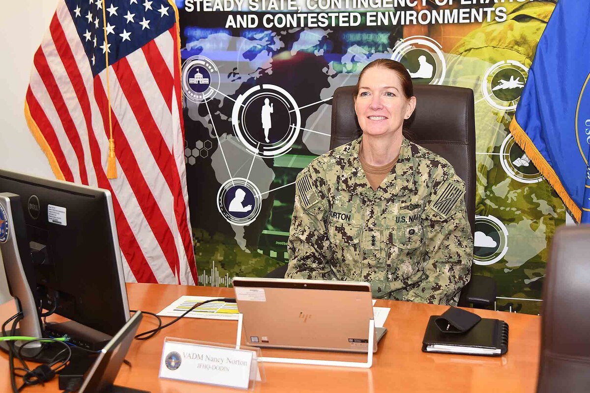 A sailor sits at a desk behind a computer.