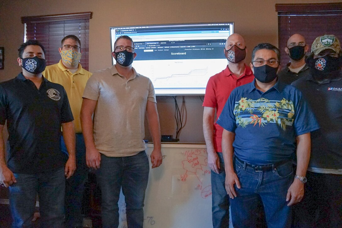 Six members from the 688th Operations Support Squadron stand in front of a television monitor.
