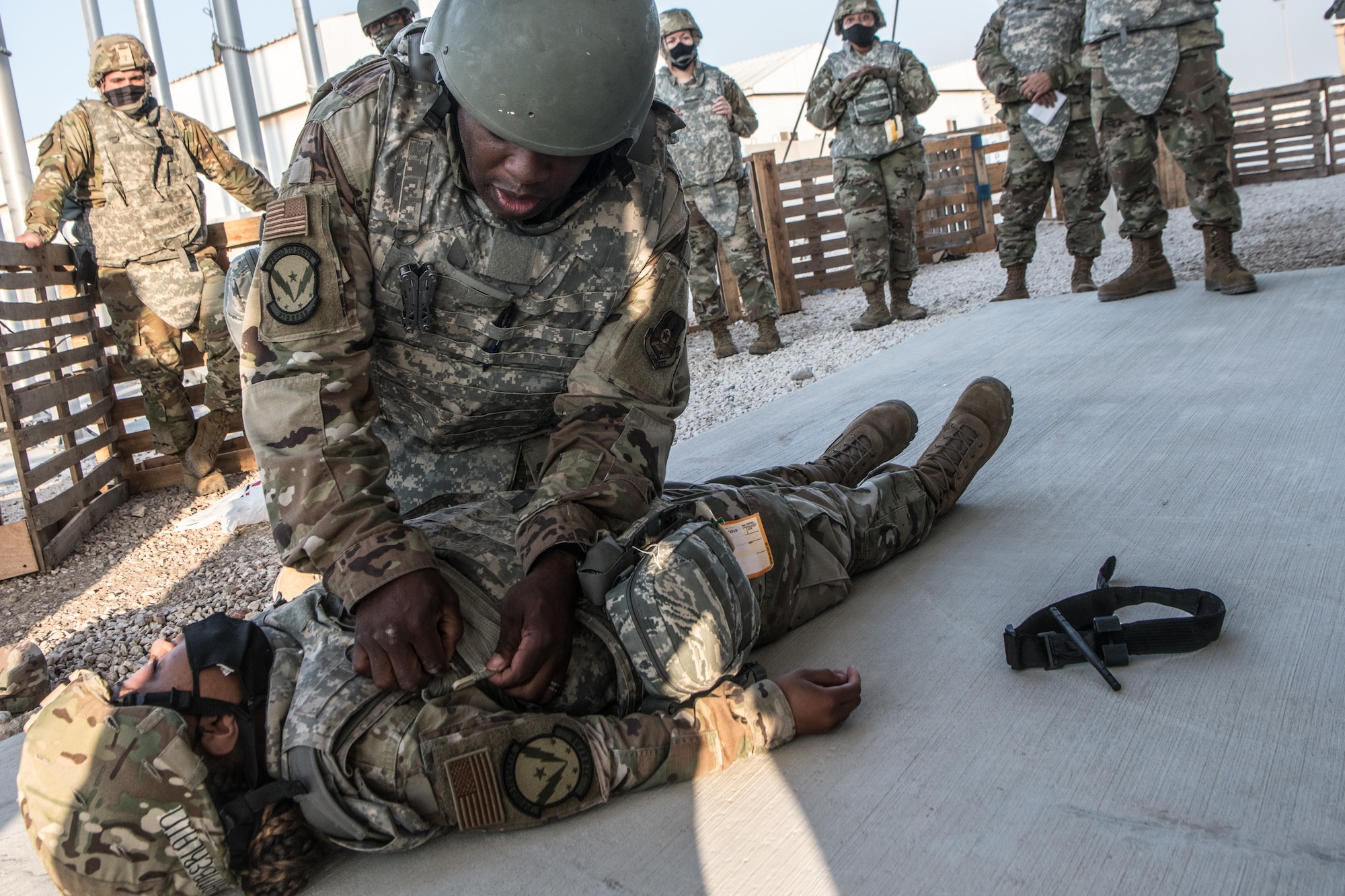an airman helps secure a bandage around the chest of another airman