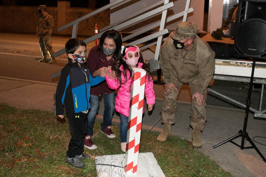 Col. Matthew Jones, 436th Airlift Wing commander and the family of currently deployed Tech Sgt. Timothy Solorio, 436th Civil Engineer Squadron firefighter, light the base Christmas tree Dec. 1, 2020, at Dover Air Force Base, Delaware. It’s a Dover AFB tradition to have the family of a deployed Airman light the Christmas tree. (U.S. Air Force photo by Mauricio Campino)