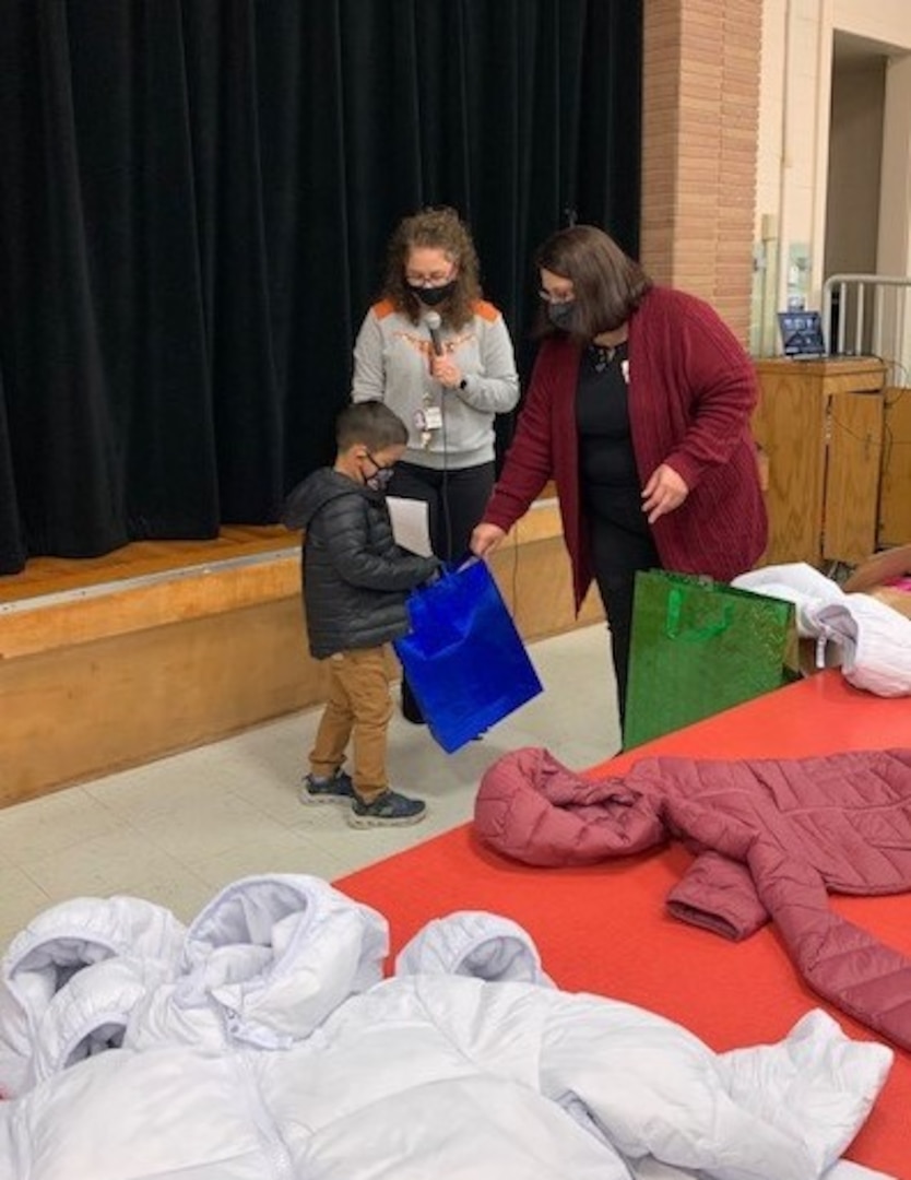 A student at Wilshire Elementary School, in San Antonio’s Northeast Independent School District, receives a coat and gifts from Lisa De La Rosa, a family specialist at the school, during a ceremony Nov. 30. The event was held virtually this year due to COVID-19.