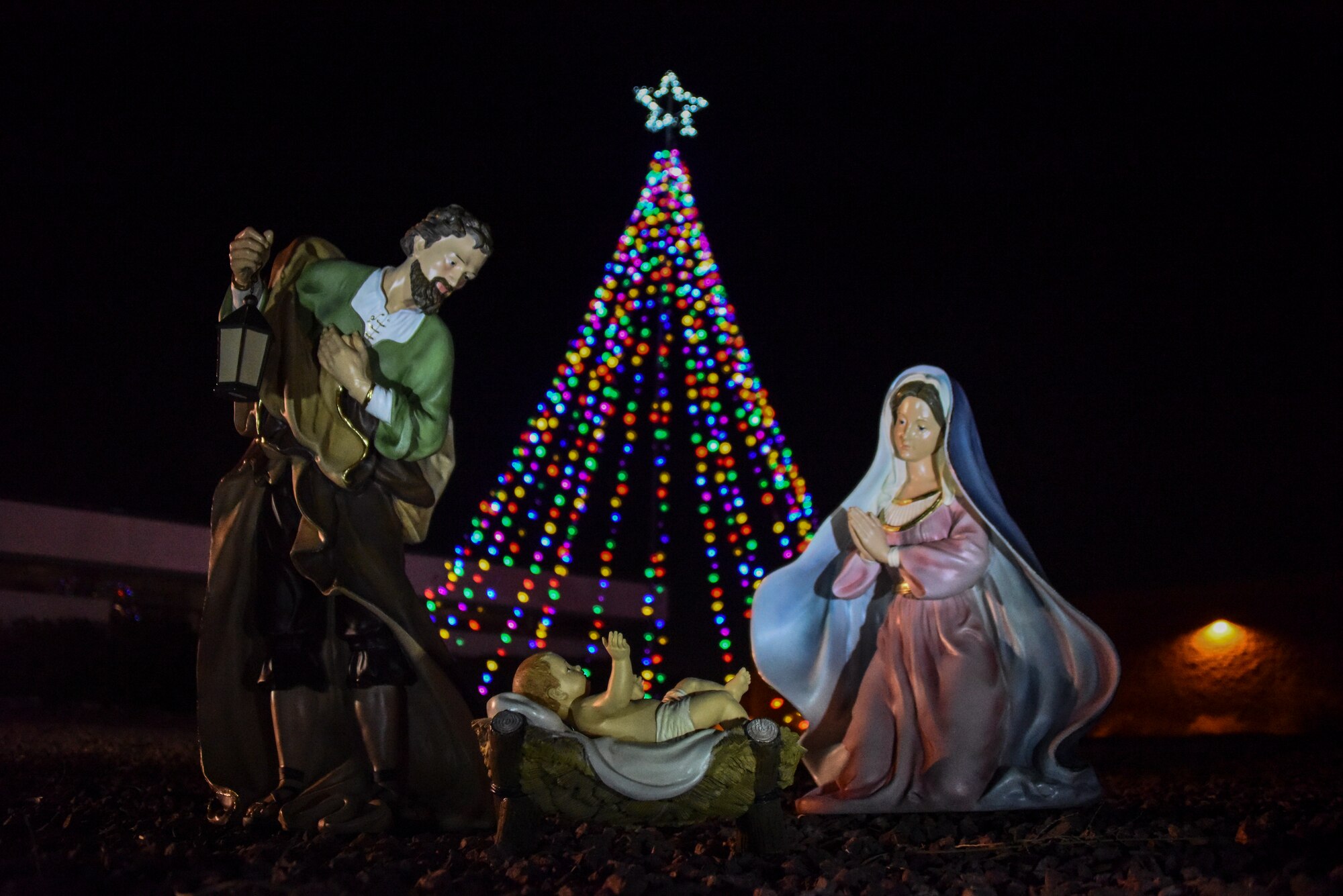 A picture of Mary, Joseph, and baby Jesus in front of a lit Christmas tree.