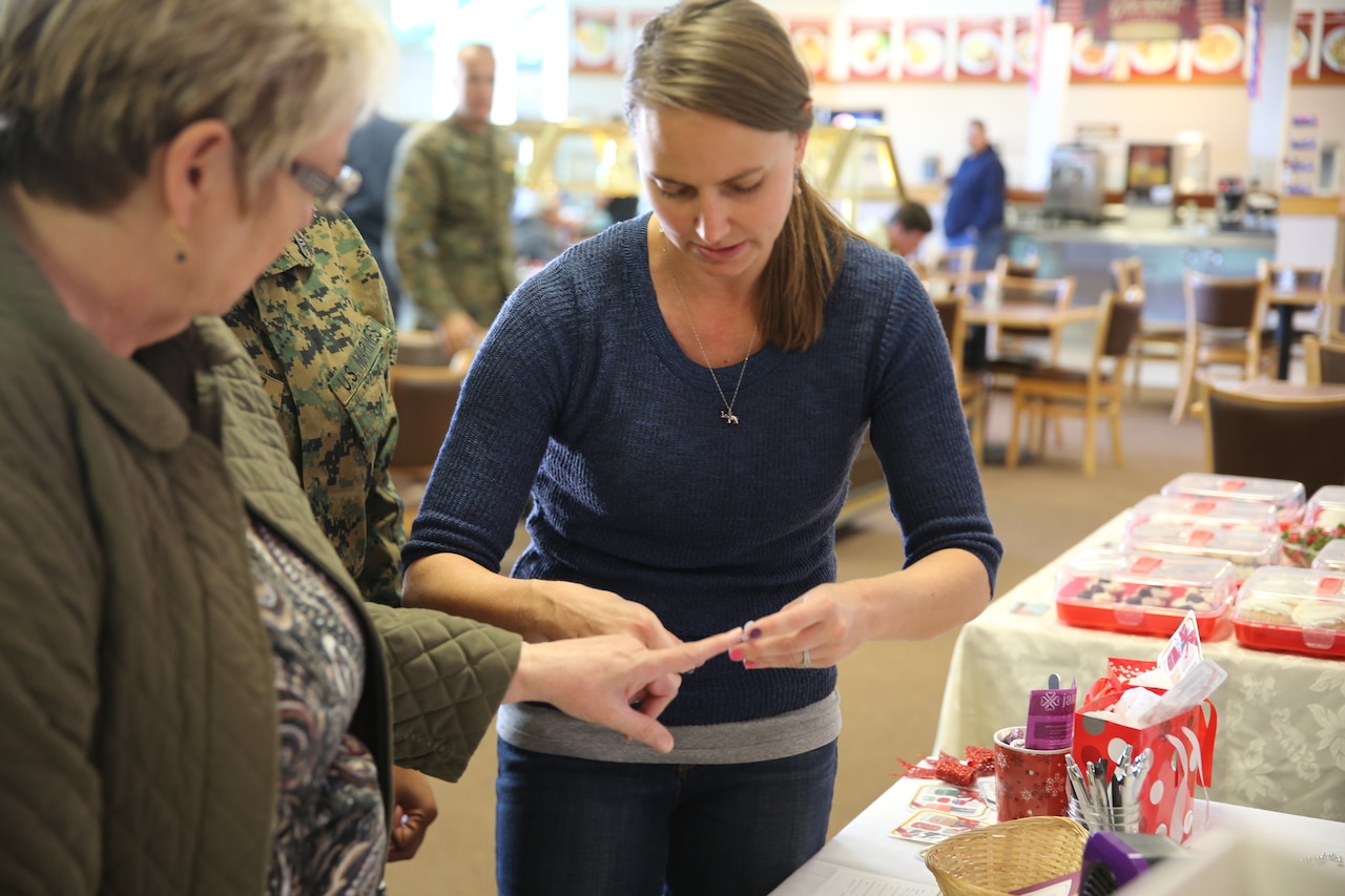 A woman touches the fingertips of another woman.