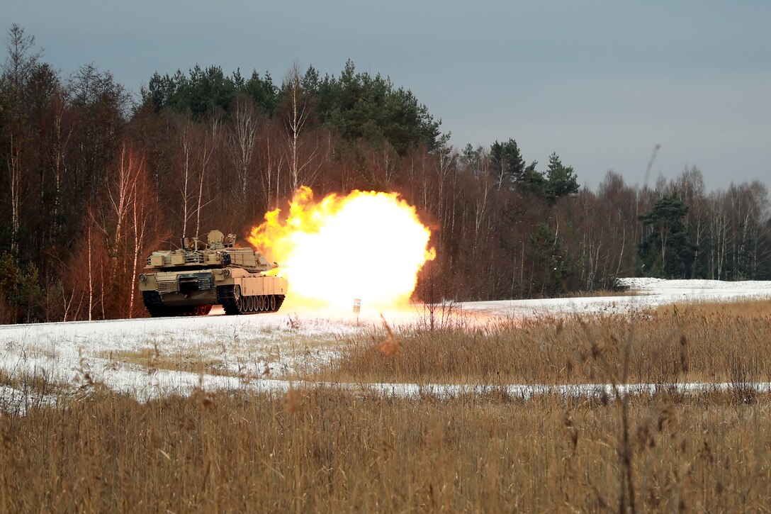 An Army tank fires in a forest.