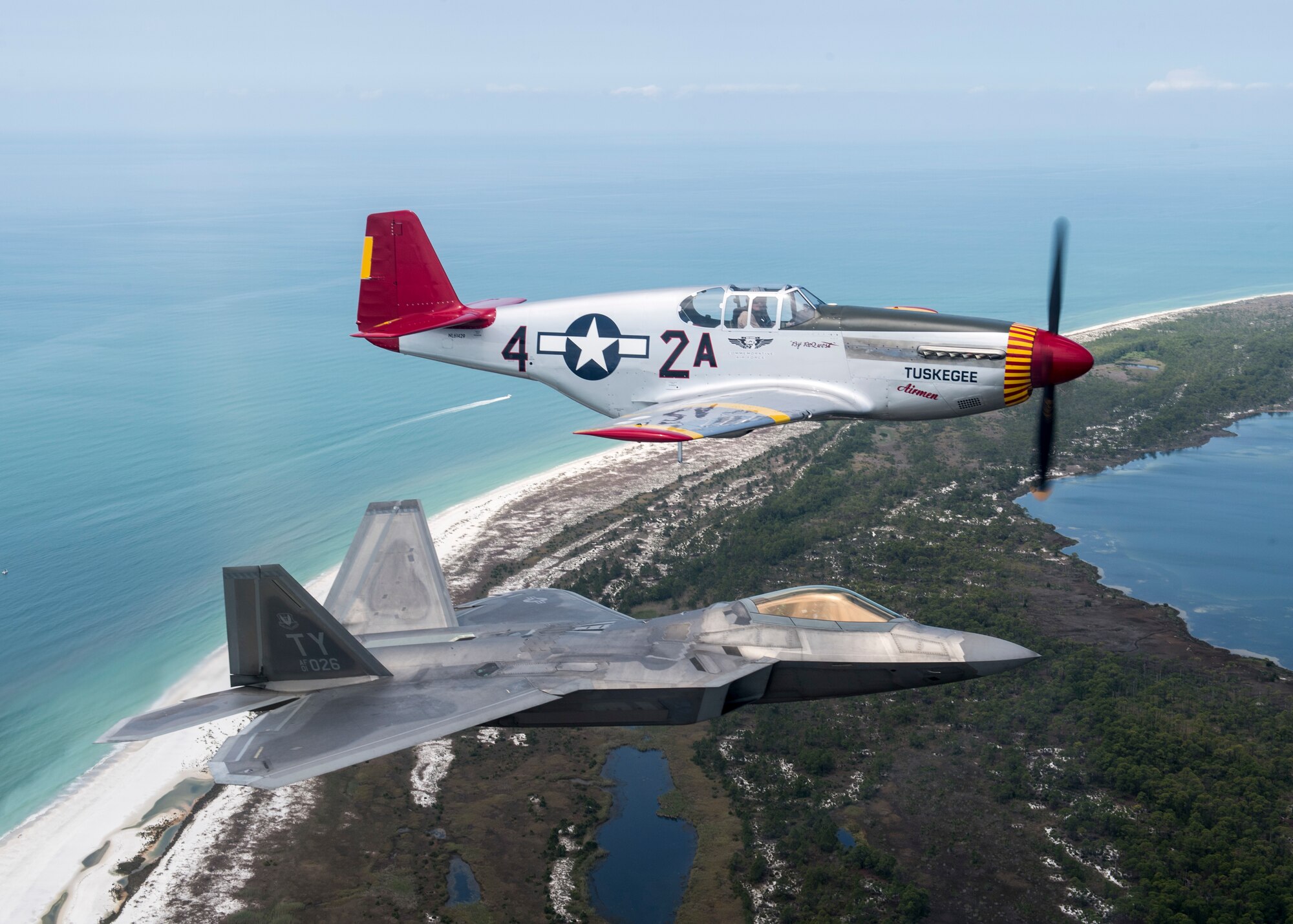 A U.S. Air Force F-22 Raptor aircraft assigned to Tyndall Air Force Base flies in formation with a World War II-era P-51 Mustang, April 22, 2017 over Panama City Beach, Fla. The aircraft flew in support of the opening ceremony of the Gulf Coast Salute Airshow at Tyndall. (U.S. Air Force photo by Staff Sgt. Jason Couillard)
