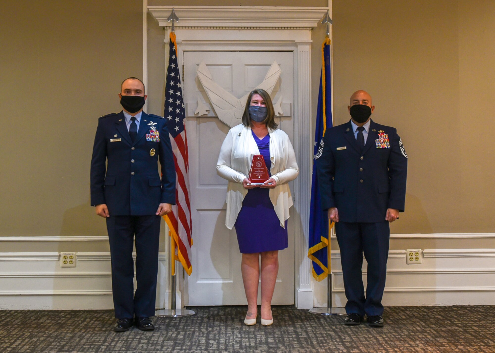 A photo of two military members and a civilian with an award.