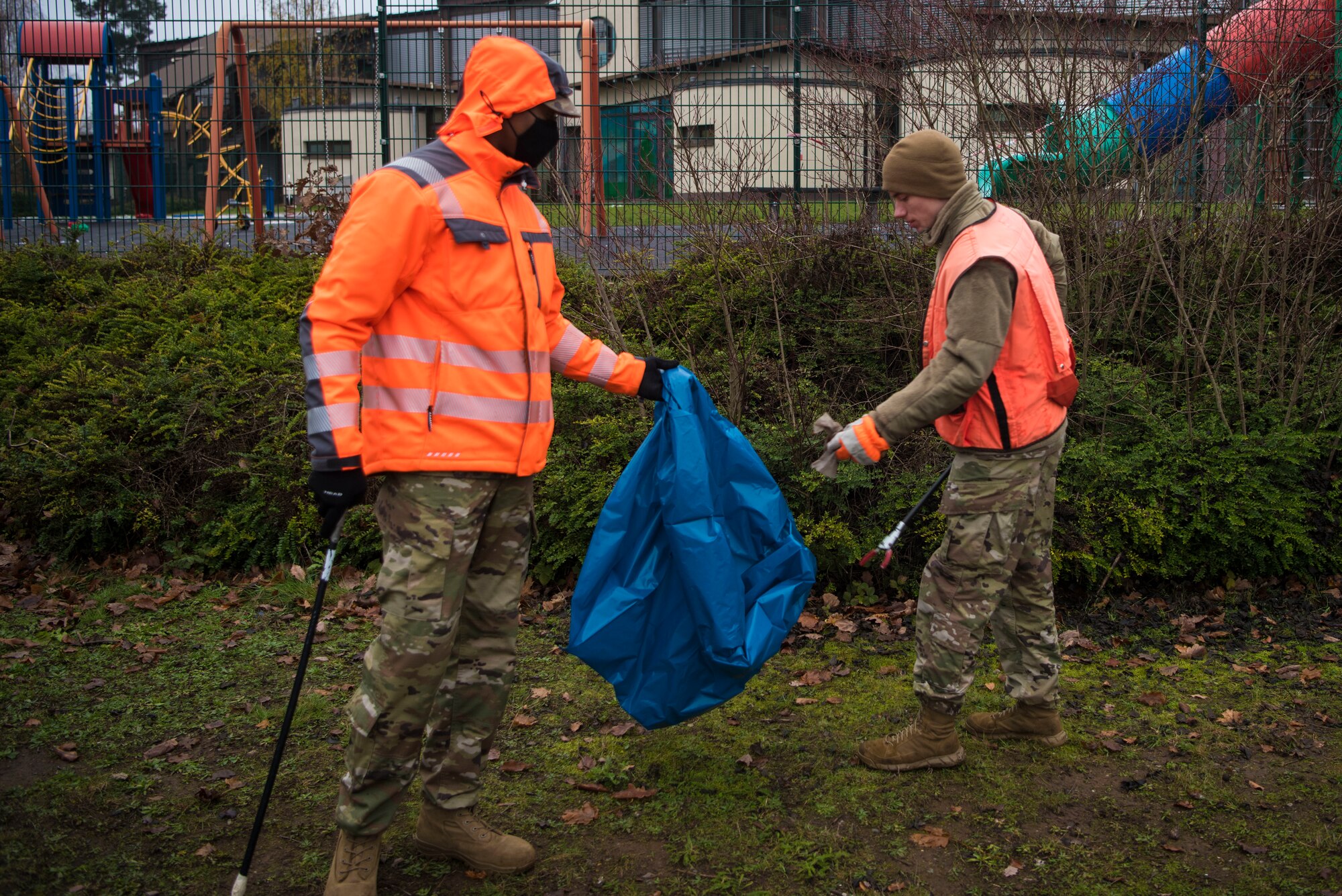 U.S. Air Force Staff Sgt. Marquette Richardson, 786th Civil Engineer Squadron facility excellence leadership team noncommissioned officer in charge, left, holds a trash bag for U.S. Air Force Airman 1st Class Zachary Hanson, 721st Aerial Port Squadron air transportation technician, during a base clean up.