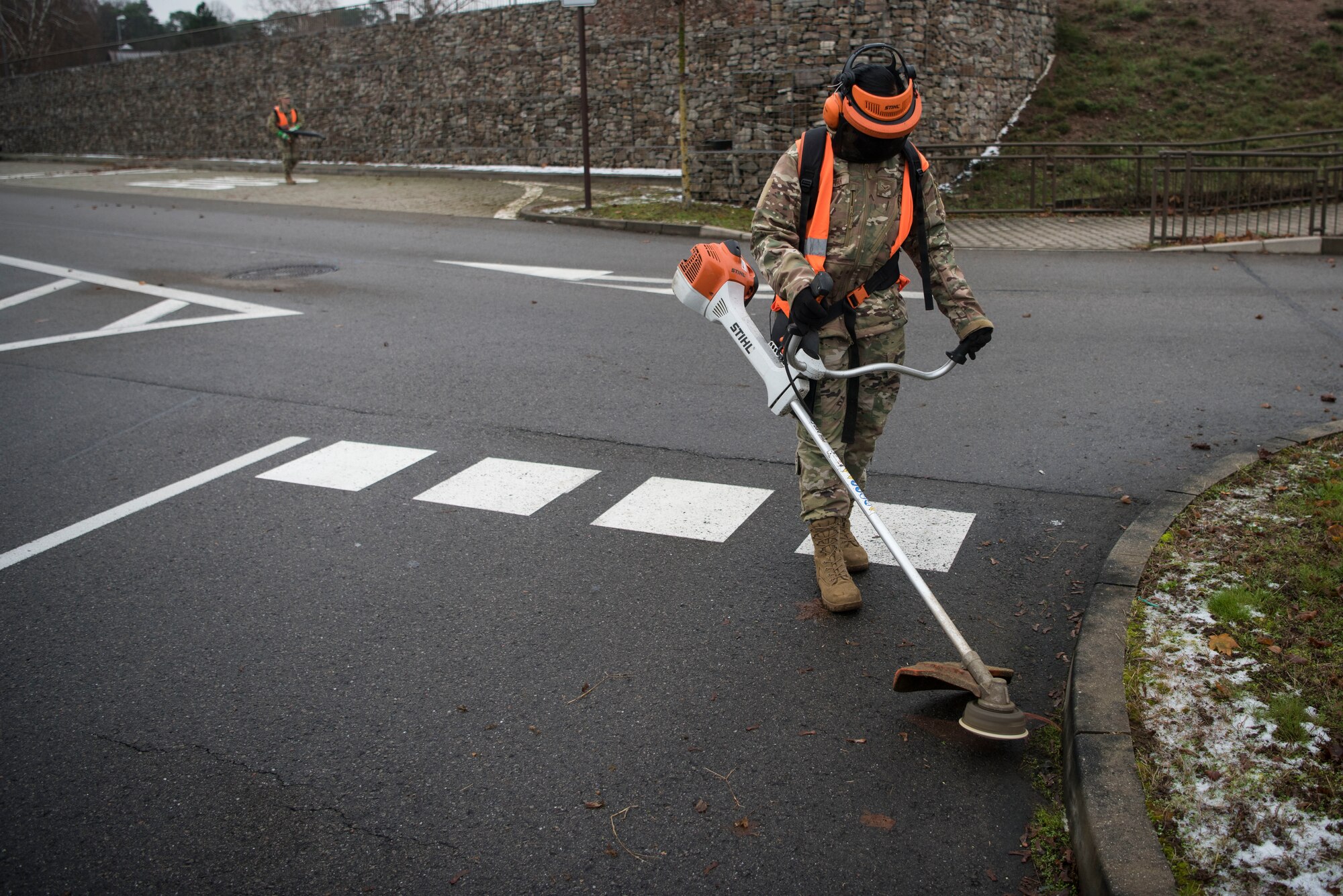 U.S. Air Force Airman 1st Class Nina Capitan, 86th Munitions Squadron operations technician, removes weeds from a parking lot during a base clean up.