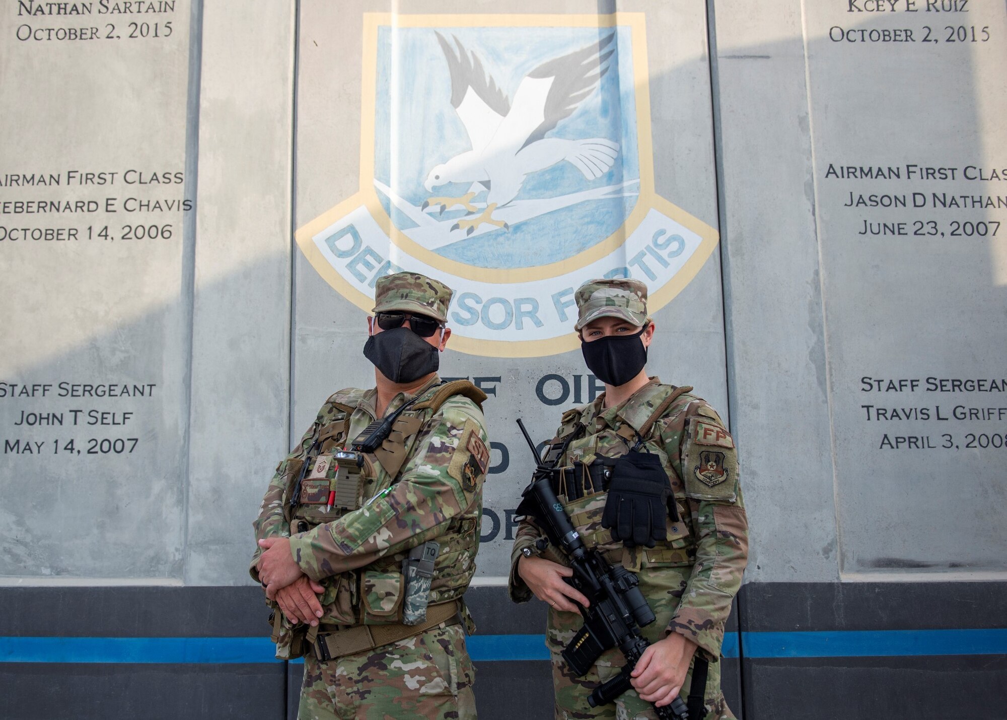 U.S. Air Force Master Sgt. Thomas Fisher, 380th Expeditionary Security Forces Squadron S30A flight chief, and Staff Sgt. Hannah Ortloff, 380th ESFS Security Forces augmentee, stand in front of t-walls with the SF insignia at Al Dhafra Air Base, United Arab Emirates, Nov. 22, 2020.