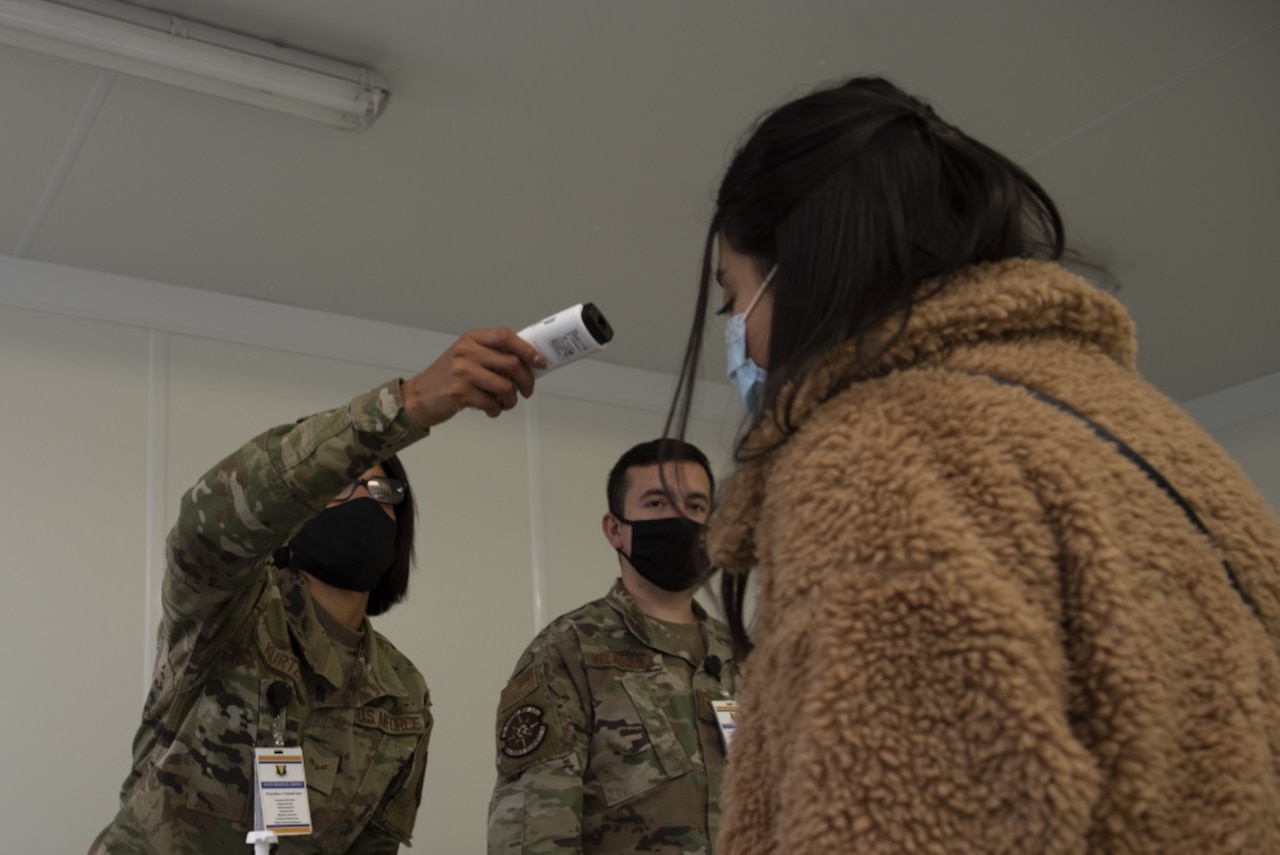 A female airman takes a patient's temperature.