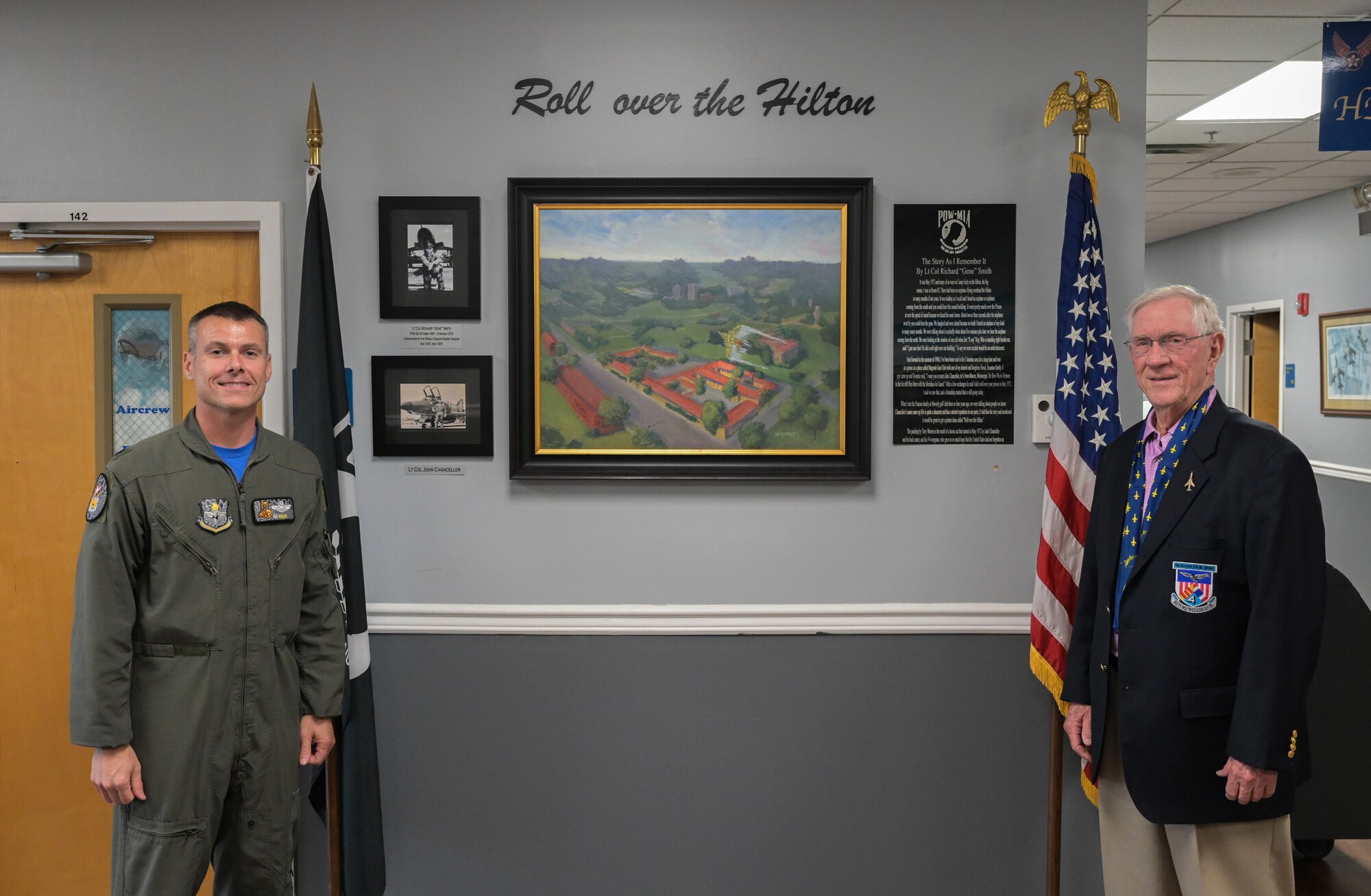 U.S. Air Force Lt. Col. Nathaniel Wilds, 50th Flying Training Squadron commander, and Retired Lt. Col. Richard “Gene” Smith, stand in front of a painting titled “Roll over the Hilton” on Nov. 13, 2020, at Columbus Air Force Base, Miss. The painting depicts an F-4 Phantom performing a roll over “The Hanoi Hilton”. (U.S. Air Force photo by Airman 1st Class Davis Donaldson)
