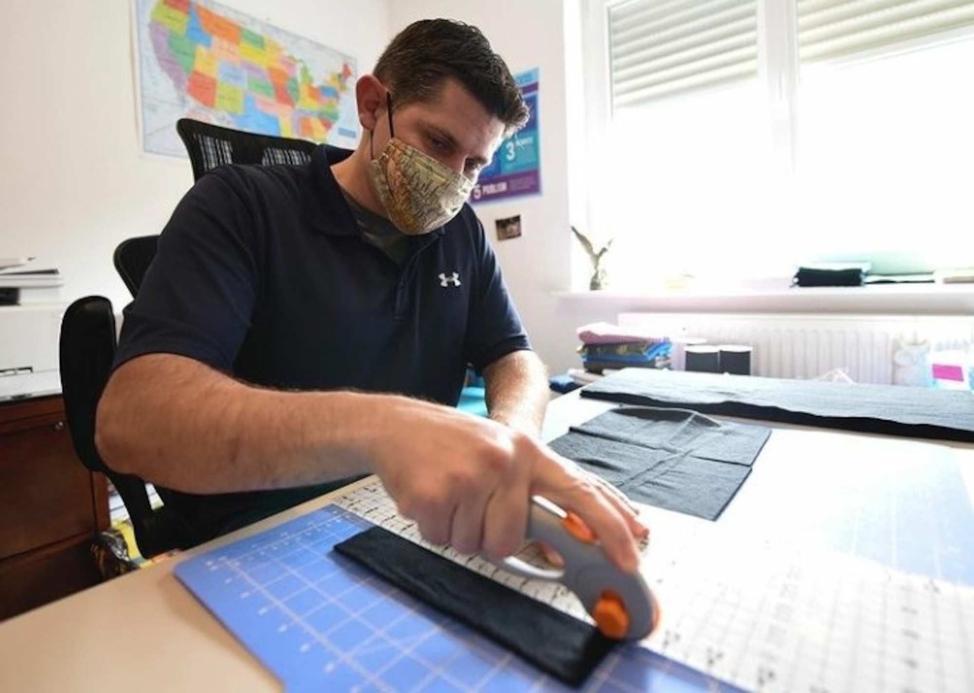 OSI 4th Field Investigations Squadron Special Agent Justin Acree cuts fabric for protective masks. SA Acree personally made 1,556 face covers for communities across Germany to help cope with the COVID-19 pandemic. (U.S. Air Force photo by SrA Elizabeth Baker, Ramstein AB/PA)