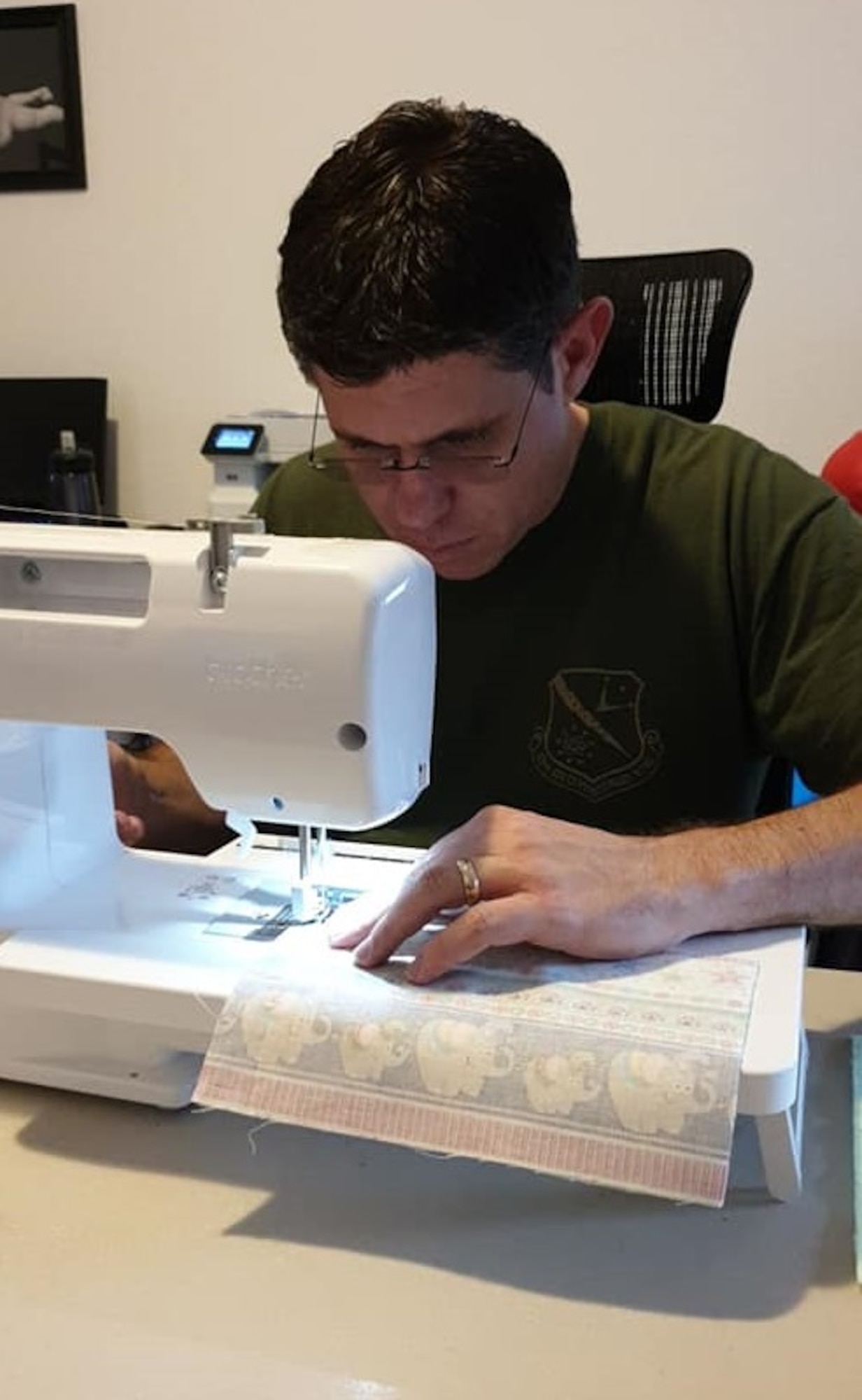 OSI 4th Field Investigations Squadron Special Agent Justin Acree sews fabric for protective masks. His spouse taught him how to use the sewing machine. SA Acree personally made 1,556 face covers for communities across Germany to help cope with the COVID-19 pandemic. (Photo by Mindi Acree)