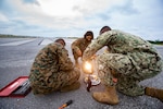 U.S. Marines with General Facilities (GF) and Navy Construction Electrician 2nd Class Ira Mozee, a native of Saint Lucie, Florida, repair threshold lights on the airfield during on-the-job training with Seabees, on Marine Corps Air Station Futenma, Okinawa, Japan, Dec. 3, 2020. When a service ticket is issued, GF Marines shadow Seabees to learn their side of the job. Seabees are trained to build and maintain permanent structures while Marines are trained in expedient construction and maintenance. The training is hands-on, teaching Marines how to build, plumb and power structures to code for long term use.