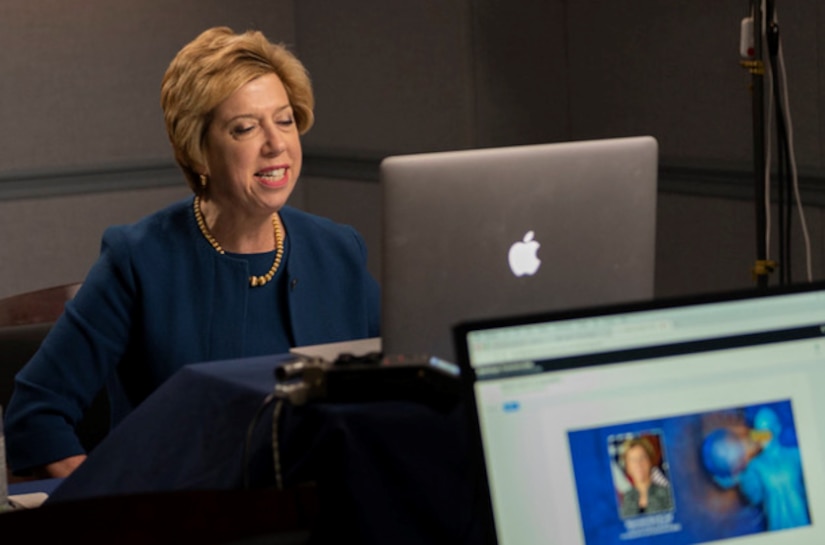 A woman sits in front of a laptop.