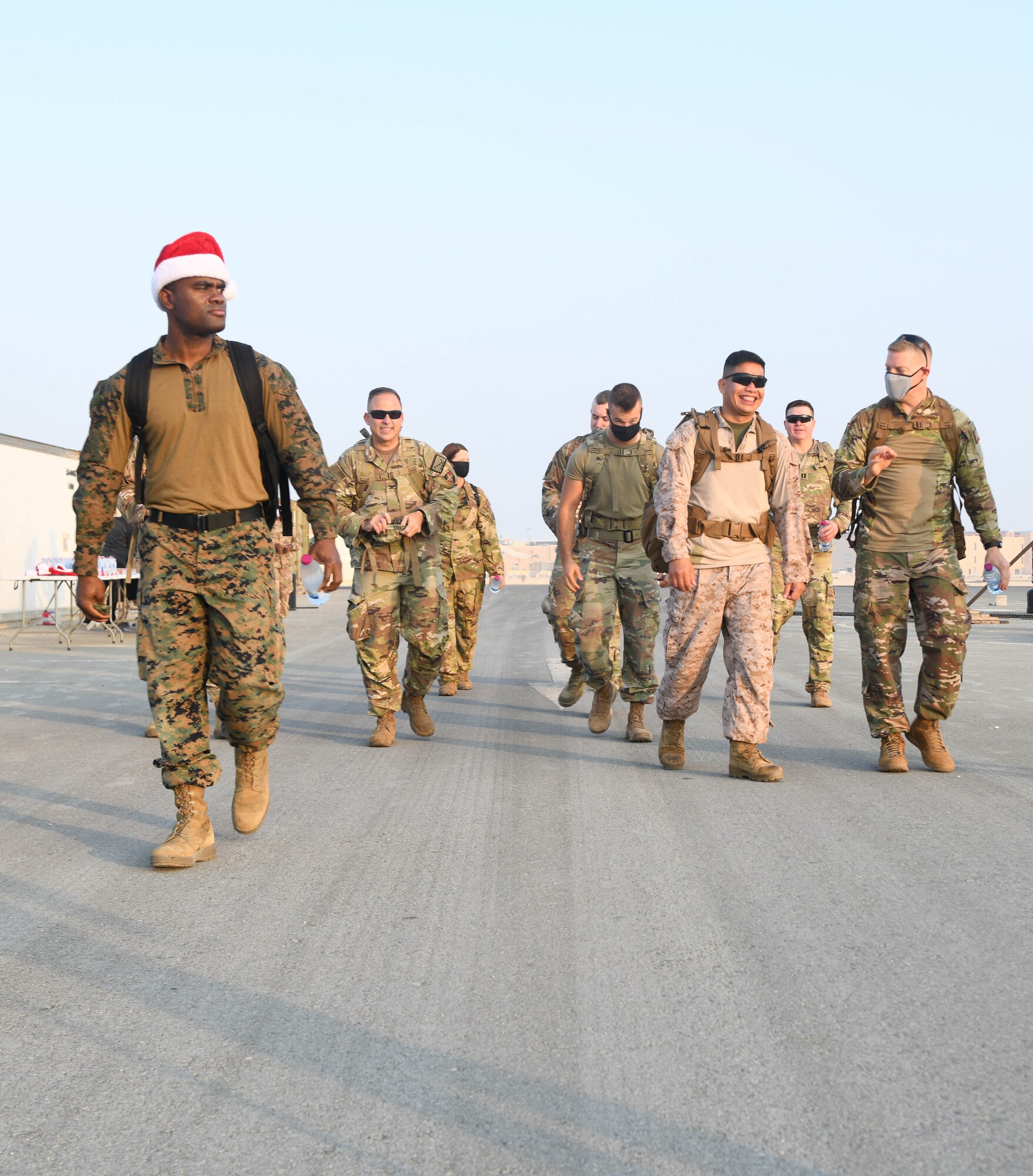 Members of the U.S. Army, Air Force, Navy and Marine Corps deployed to Al Udeid Air Base, Qatar, begin the Christmas Ration Ruck March on Dec. 1, 2020. The charitable event brought together the combined military team for a 2-mile ruck march and partnered with the USO to donate toiletries, children's books and food items back to the United States. (U.S. Air Force photo by Staff Sgt. Kayla White)