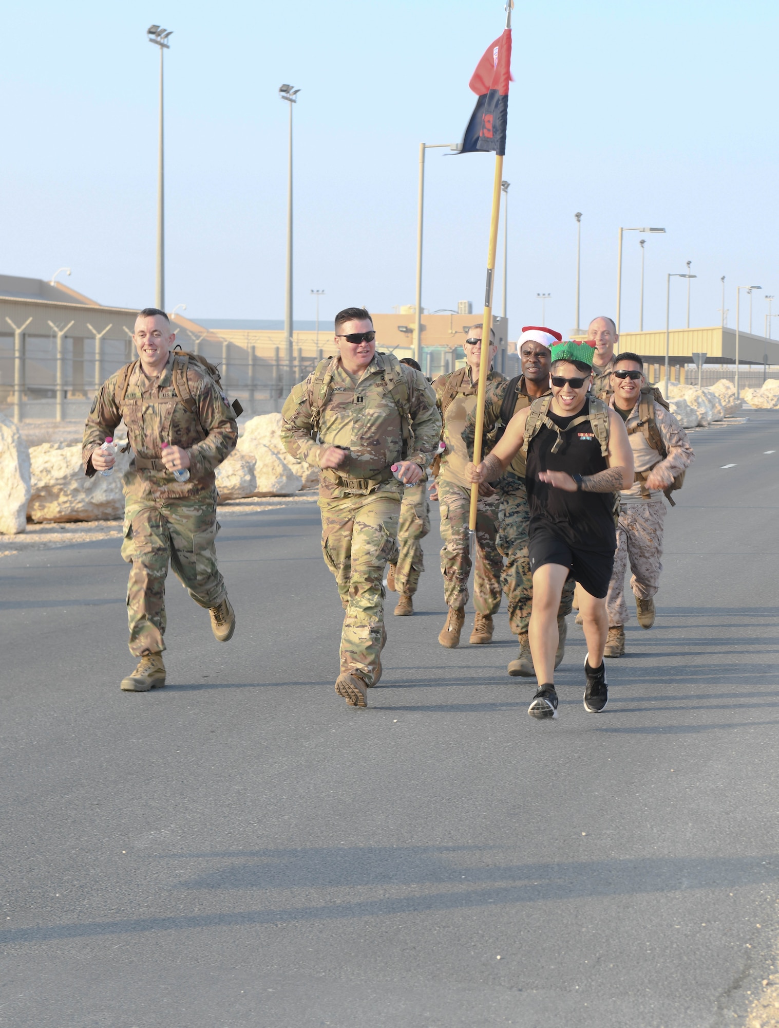 Members of the U.S. Army, Air Force, Navy and Marine Corps deployed to Al Udeid Air Base, Qatar, participate in the Christmas Ration Ruck March on Dec. 1, 2020. The charitable event brought together the combined military team for a 2-mile ruck march and partnered with the USO to donate toiletries, children's books and food items back to the United States. (U.S. Air Force photo by Staff Sgt. Kayla White)