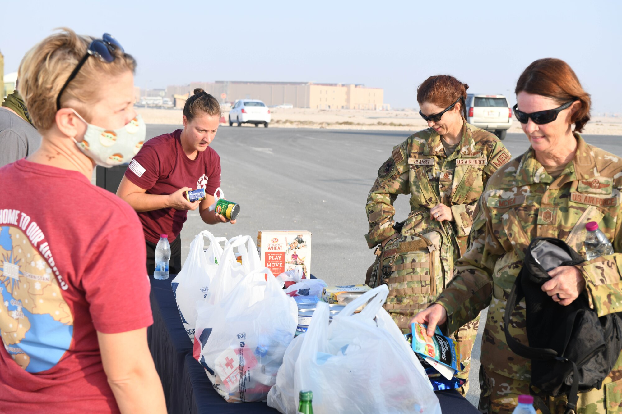 U.S. Air Force Senior Airman Chanda Olson, Maj. Rachel Blanset and Chief Master Sgt. Saudi McVea, all assigned to the 379th Expeditionary Aeromedical Evacuation Squadron at Al Udeid Air Base, Qatar, donate food after completing the Christmas Ration Ruck March on Dec. 1, 2020. Members of the Air Force, Army, Navy and Marine Corps deployed to Al Udeid AB came together for the 2-mile charity event and partnered with the USO to donate toiletries, children's books and food items back to the United States. (U.S. Air Force photo by Staff Sgt. Kayla White)