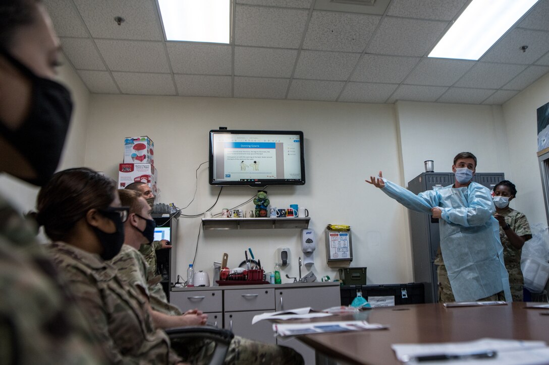 Airman demonstrates donning and doffing a disposable gown for COVID-19 testing