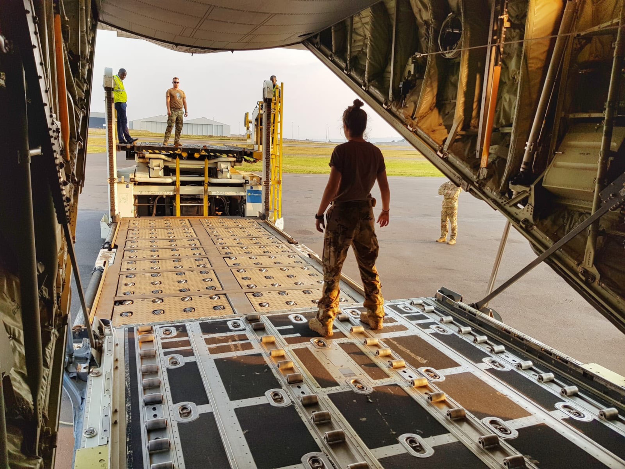 A woman stands on C-130 ramp while loading equipment