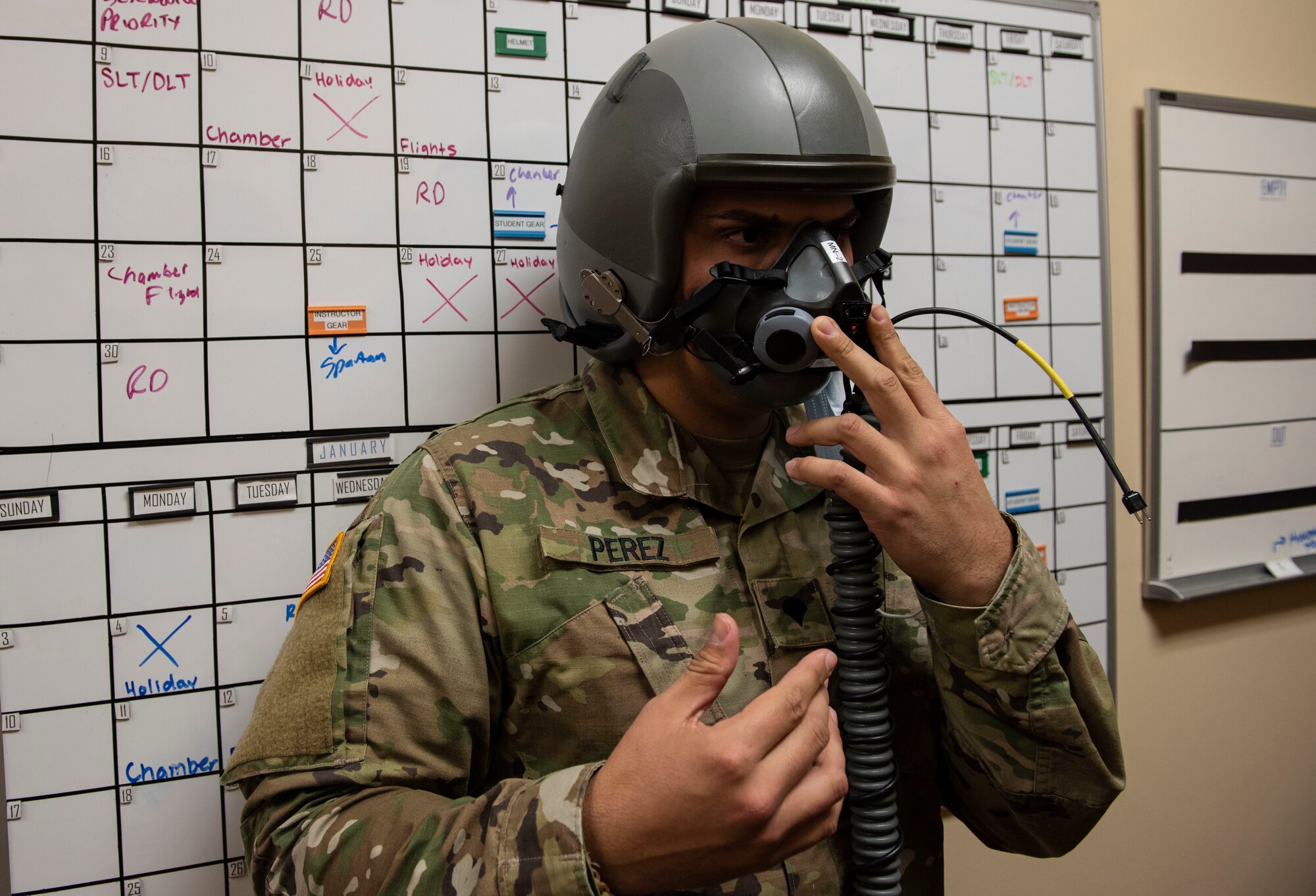 Spc. Santiago Perez, 204th Military Intelligence Battalion cryptologic linguist, gets fitted for a helmet and mask before going to the chamber on Nov. 23, 2020, Laughlin Air Force Base, Texas. This equipment is used to help breathe when in high altitudes. (U.S. Air Force photo by Airman 1st Class David Phaff)