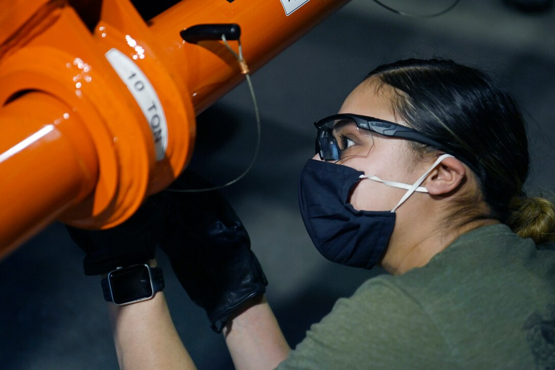 A soldier wearing protective gear works on vehicle.