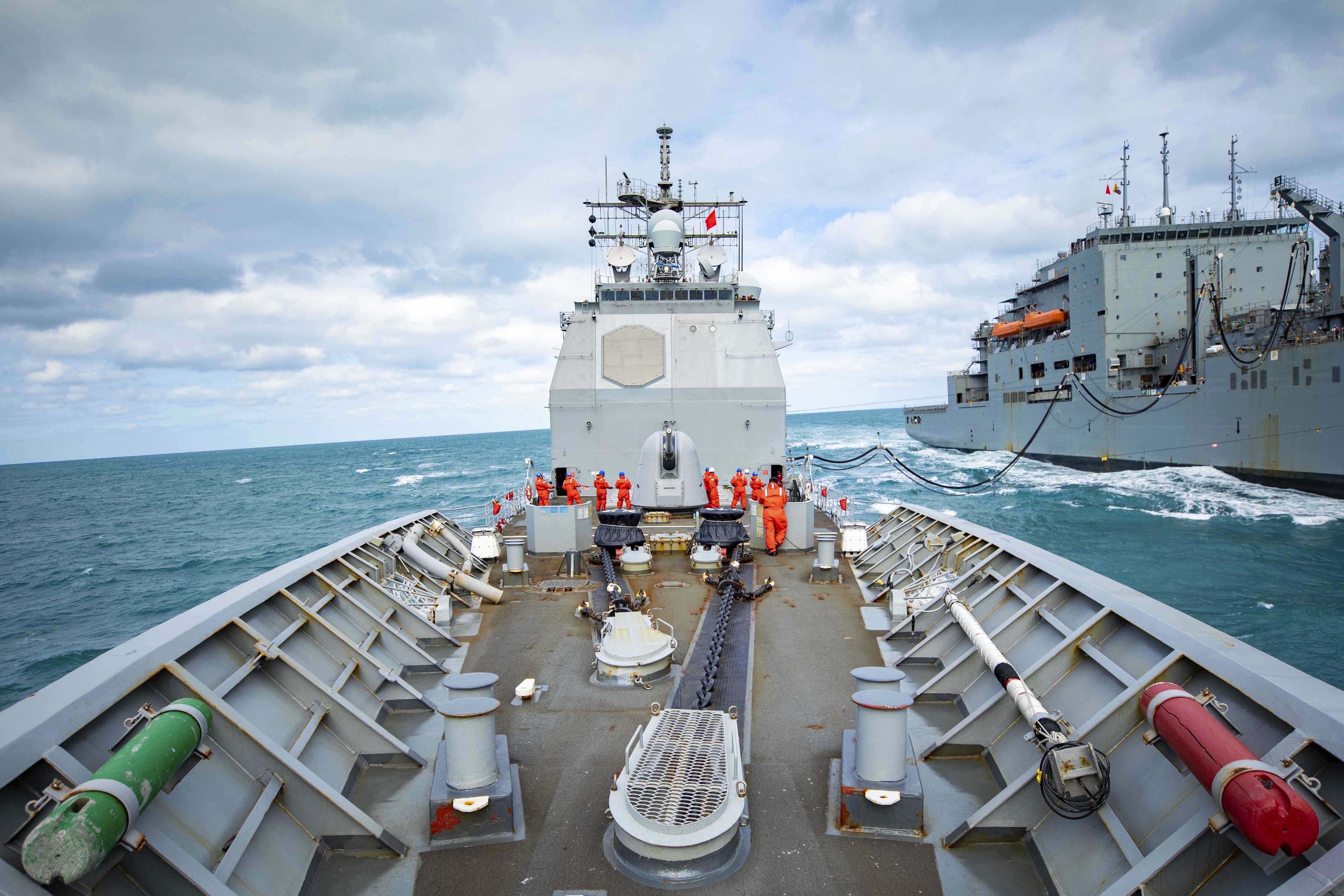 Two ships sail side by side in blue waters.