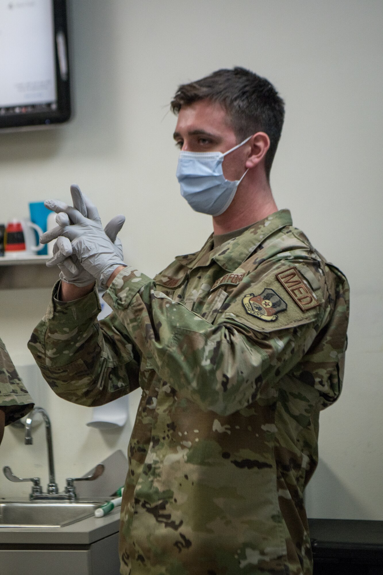 An Airman puts on disposable gloves