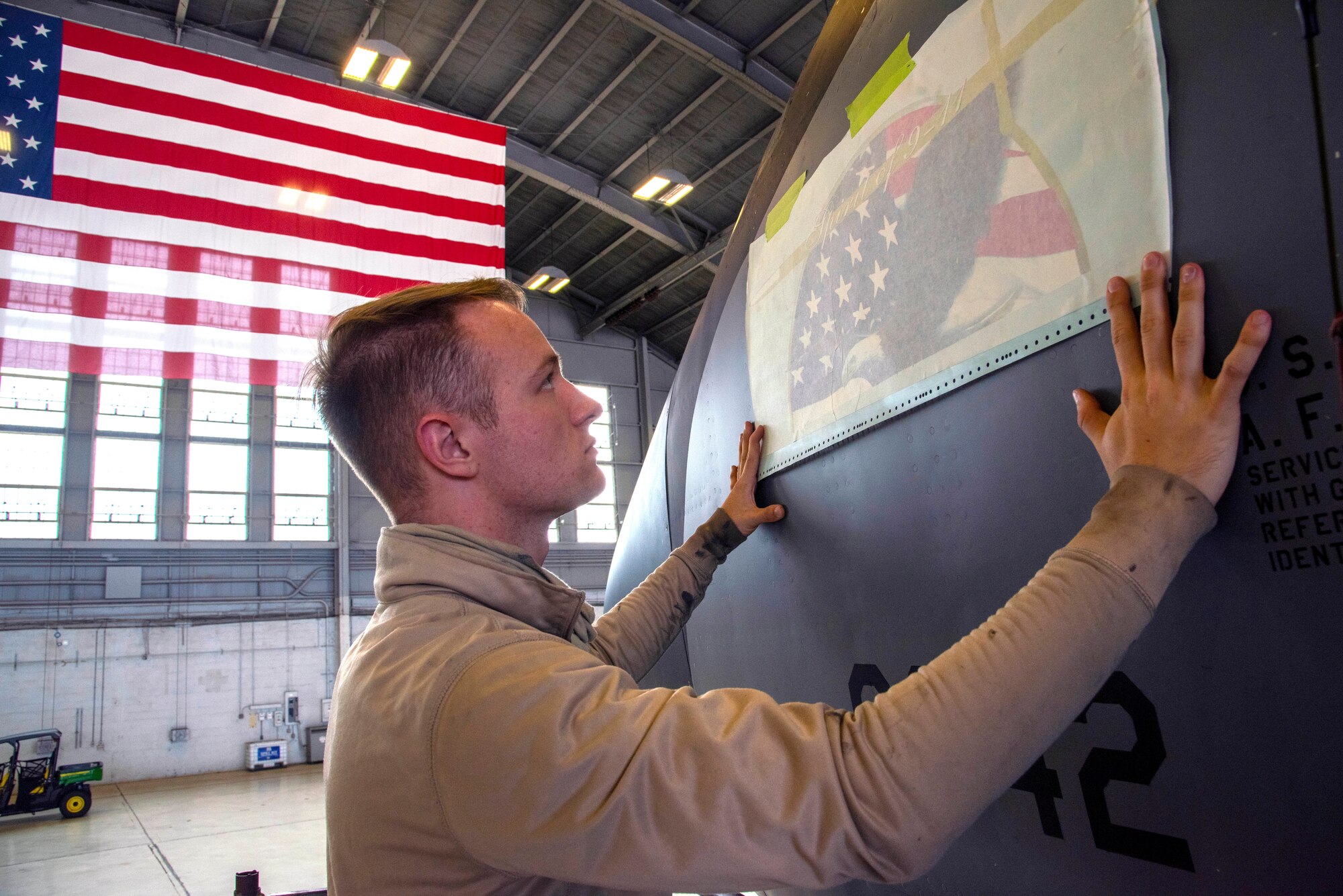 Senior Airman Alex Dixon, a 6th Maintenance Squadron aircraft structural maintainer, places a 9/11 remembrance decal on a KC-135 Stratotanker aircraft in Hangar 3 at MacDill Air Force Base, Fla., Dec. 4, 2020. The decal has a bald eagle in front of the American flag with Todd Beamer’s call-to-action, “Let’s Roll”, rallying cry during United Flight 93 in which the passengers took back control from four al-Qaeda terrorists. (U.S. Air Force photo by Senior Airman Scott Warner)