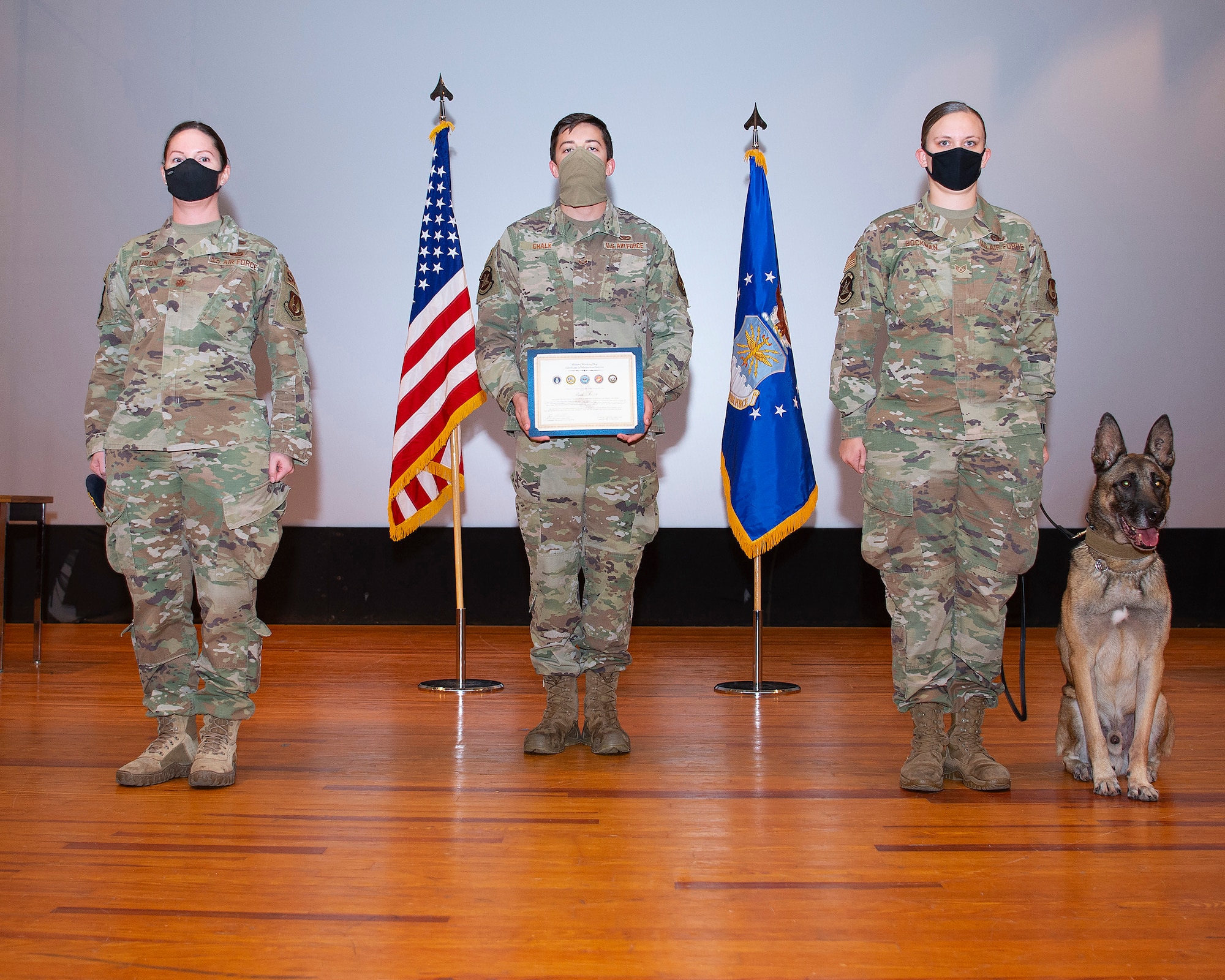 Military Working Dog Rudo and his handler, Staff Sgt. Lacey Bockman, 88th Security Forces Squadron, are presented with Rudo’s Military Working Dog Certificate of Meritorious Service by Maj. Julie Roloson, 88th SFS commander, during his retirement ceremony in the Wright-Patterson Air Force Base, Ohio, theater Nov. 16, 2020. During his more than eight years at Wright-Patterson Rudo is credited with more than 3000 random anti-terrorism measures, more than 3000 foot patrols and approximately 5000 hours of explosive detection. (U.S. Air Force photo by R.J. Oriez)