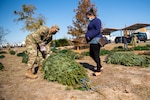 U.S. Air Force Master Sgt. Kevin Yamaguchi, 149th Aircraft Maintenance Squadron 1st Sgt., helps a military spouse with a Christmas tree during the Trees for Troops event Dec. 3, 2020, at Joint Base San Antonio-Lackland, Texas.