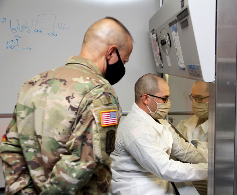 Spc. Darius Torres, of Littlefield, Texas, a medical laboratory technician assigned to Public Health Activity-Fort Lewis, demonstrates command’s new COVID-19 pooled testing procedures to Brig. Gen. Jack M. Davis, commanding general of Regional Health Command-Pacific, at PHC-P’s new COVID-19 Surveillance Testing Laboratory, Dec. 3, 2020. (U.S. Army photo by Christopher Larsen, RHC-P Public Affairs)