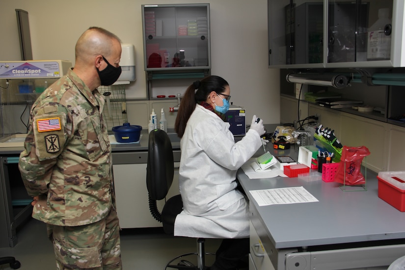 Milagros Sola, a microbiologist with Pubic Health Command-Pacific, works with ribonucleic acid, or RNA, while demonstrating the command’s new COVID-19 pooled testing procedures to Brig. Gen. Jack M. Davis, commanding general of Regional Health Command-Pacific, at PHC-P’s new COVID-19 Surveillance Testing Laboratory, Dec. 3, 2020. (U.S. Army photo by Christopher Larsen, RHC-P Public Affairs)