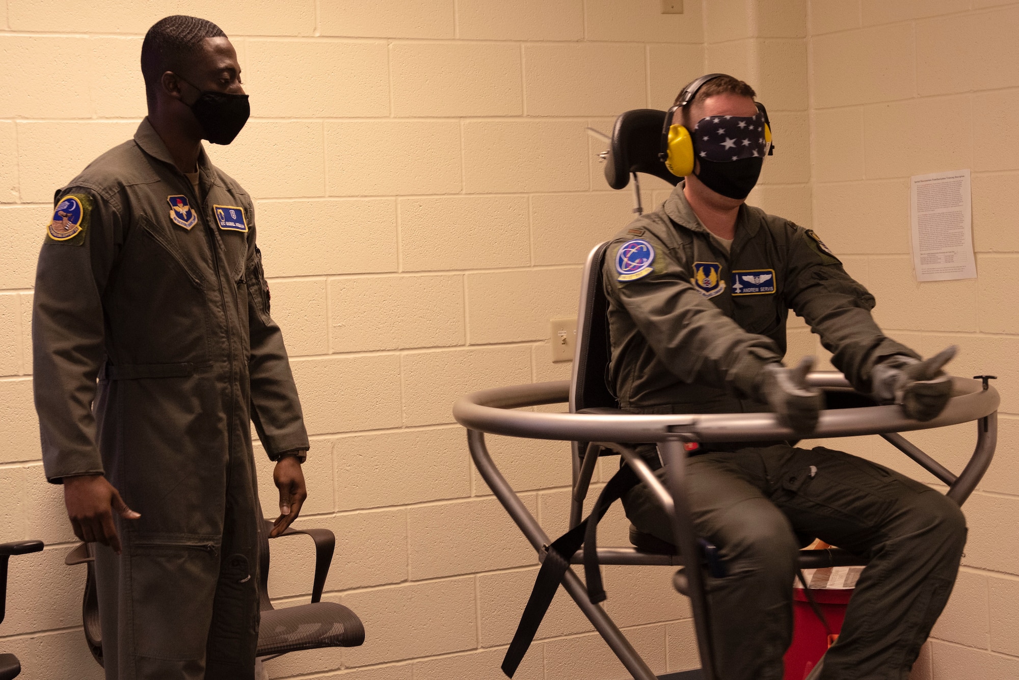 Airman 1st Class Gaddiel Acquaah, 47th Operations Support Squadron aerospace physiology technician, spins 2nd. Lt. Andrew Servis, 586th Flight Test Squadron, a flight test engineer, in a Barany Chair on Nov. 23, 2020, Laughlin Air Force Base, Texas. The Barany Chair spins a person carefully at first and progressively becomes more violent, and is designed to train pilots to avoid throwing up when their inner ear becomes disoriented while flying. (U.S. Air Force photo by Airman 1st Class David Phaff)